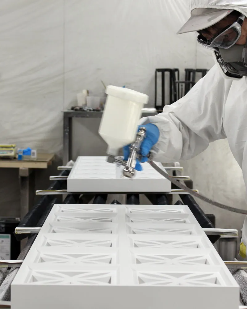パネルの塗装。作業服とマスク着用での幾何学パターンパネルへのスプレー施工